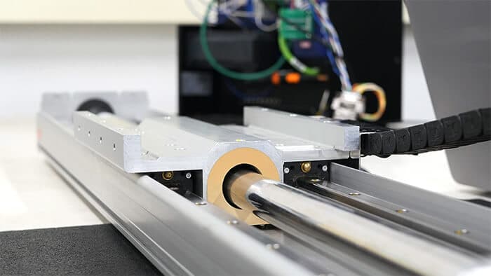 Close up photo of a Nippon Pulse Linear Shaft Motor with a KEB VFD in the background